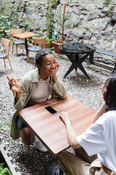 Cheerful Multiethnic Friends Talking Smartphone Outdoor Cafe — Stok fotoğraf