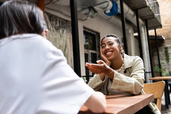 Smiling African American Woman Talking Blurred Friend Outdoor Cafe — kuvapankkivalokuva