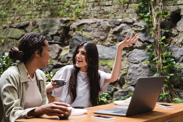 Positive Multiethnic Girlfriends Coffee Talking Gadgets Outdoor Cafe — Stok fotoğraf