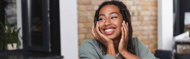 Smiling african american woman looking away in cafe, banner 
