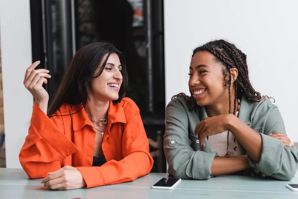 Happy Multiethnic Girlfriends Talking Cellphones Cafe — Stock Fotó