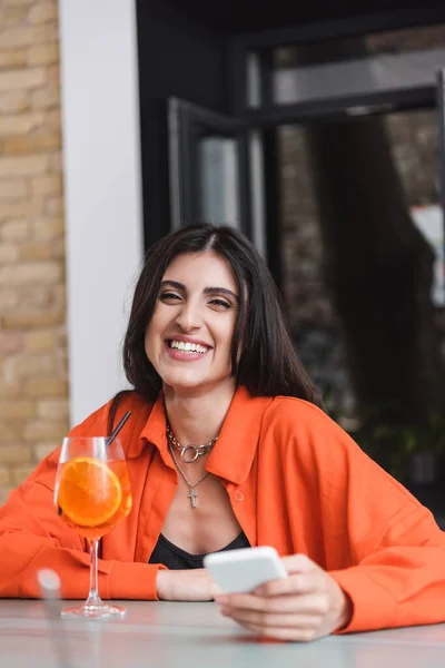 Cheerful Brunette Woman Holding Blurred Smartphone Cocktail Cafe — 스톡 사진
