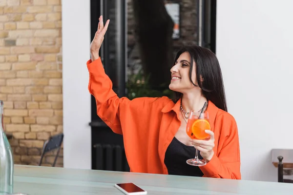 Smiling Woman Holding Cocktail Waving Hand Smartphone Cafe — Foto de Stock