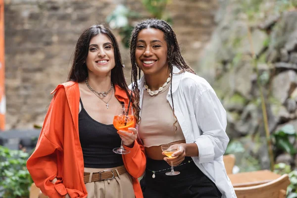 Positive Multiethnic Women Holding Cocktails Looking Camera Terrace Cafe — Stock Fotó