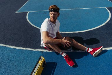 high angle view of basketball player sitting on court with ball and boombox