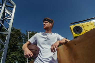 low angle view of young basketball player looking away near boombox