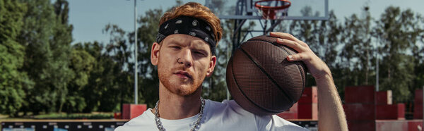 redhead basketball player in headband holding ball and looking at camera, banner