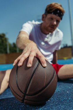 selective focus of ball near young basketball player on blurred background