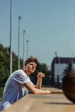 young sportive man in bandana and white t-shirt looking away outdoors