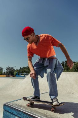 young and stylish skater jumping from ramp in skate park