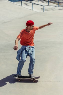 full length of man in beanie and gumshoes skateboarding with outstretched hands