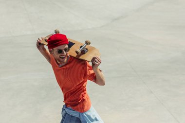 high angle view of cheerful man carrying skate on shoulders