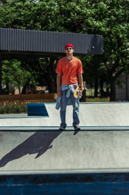 full length of fashionable skater standing on ramp in skate park