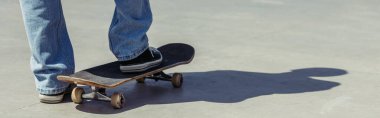 partial view of man in gumshoes standing on skateboard, banner