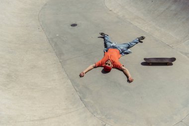 high angle view of cheerful man relaxing near skateboard on ramp