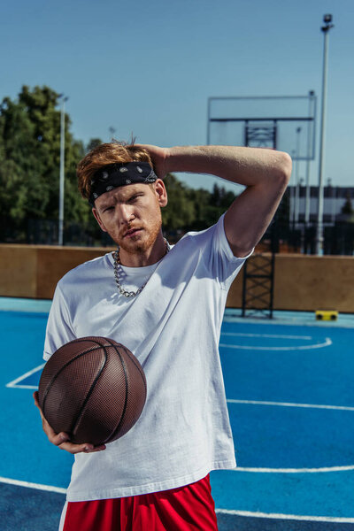 redhead sportsman in bandana holding ball and looking at camera