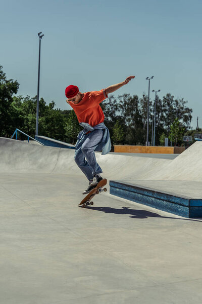 молодой человек в модном летнем наряде прыгает со скейтборда
