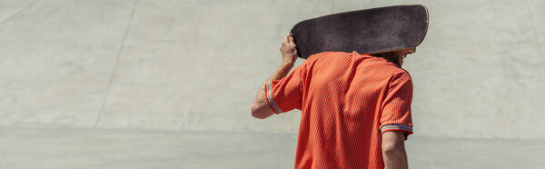 Вид сзади человека, идущего с скейтбордом на плечах, баннер