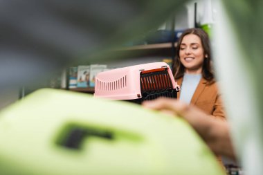 Blurred smiling woman holding animal cage in pet shop