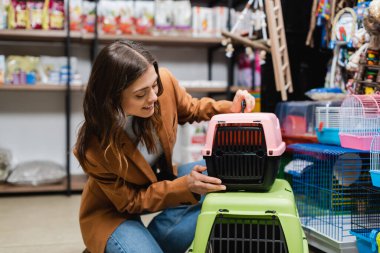 Smiling woman looking at animal cages in pet shop 