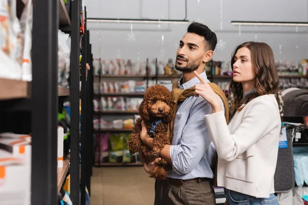 Woman Pointing Finger Muslim Boyfriend Holding Poodle Pet Shop — Stockfoto