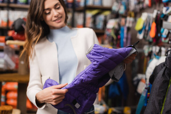 Размытая женщина держит пиджак в магазине 