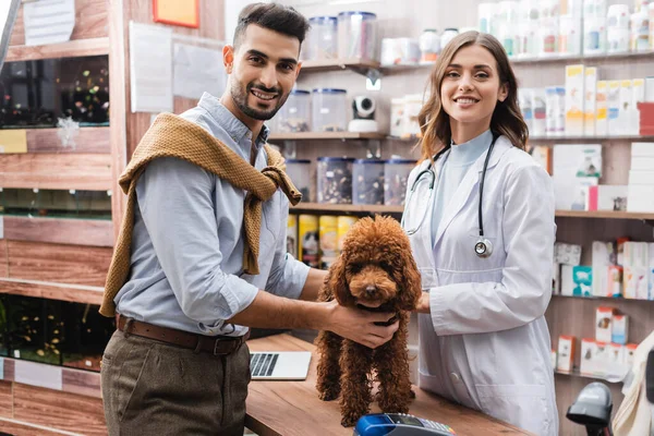 Cheerful Muslim Man Looking Camera Poodle Veterinarian Pet Shop —  Fotos de Stock