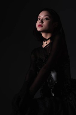 portrait of young asian woman in gothic outfit with corset isolated on black