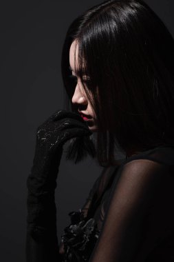side view of sensual asian woman in glove isolated on dark grey
