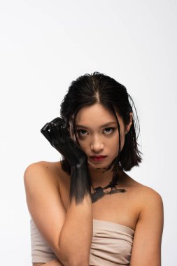 young asian woman with hand and body in black paint posing isolated on white