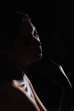 silhouette of young asian woman with paint on hand touching face isolated on black