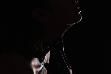 cropped view of woman with paint on hand touching neck isolated on black