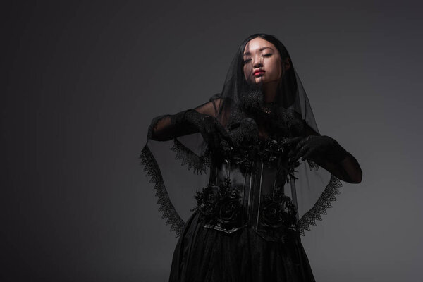 young asian woman in gothic outfit with black veil posing isolated on grey