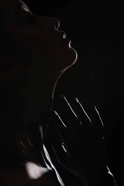 silhouette of young asian woman touching face isolated on black