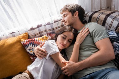 High angle view of man hugging girlfriend on bed in camper van 