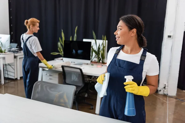 Mujer Racial Feliz Con Detergente Trapo Mirando Oficina Limpieza Colega —  Fotos de Stock