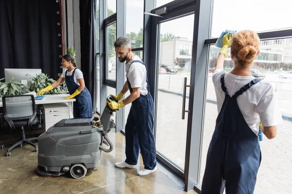 Man Med Elektriska Golv Skrubber Maskin Nära Interracial Kvinnor Rengöring — Stockfoto