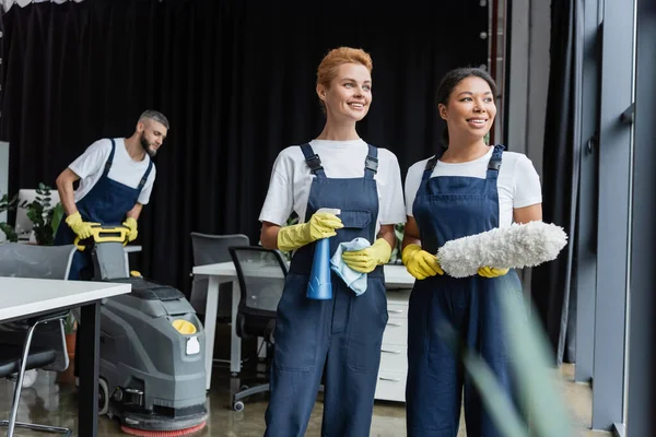 Happy Interracial Women Cleaning Supplies Looking Away Man Floor Scrubber — Stock Photo, Image