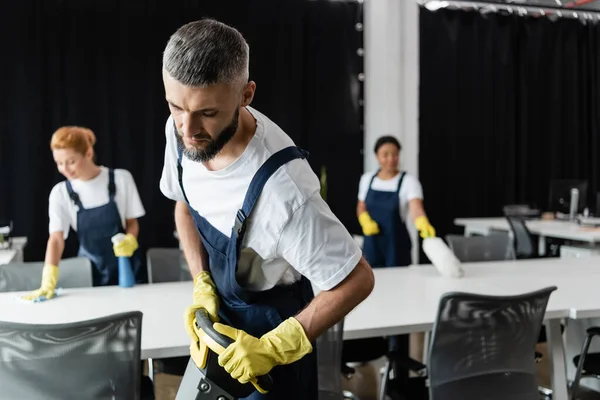 Чоловік Підлогою Стерильною Машиною Поблизу Міжрасових Жінок Прибирають Столи Розмитому — стокове фото