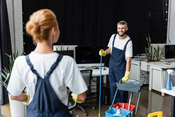 Happy Man Standing Cart Cleaning Supplies Looking Blurred Colleague — Stock Photo, Image