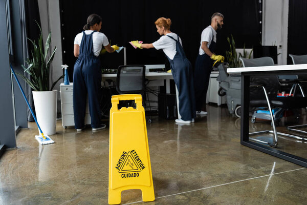 attention sign board near multiethnic professional team cleaning modern office 