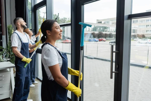 Kıyafetleri Içinde Genç Çift Irklı Bir Kadın Ofis Pencerelerini Temizleyen — Stok fotoğraf