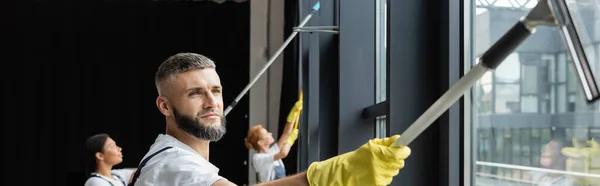 Man Met Baard Wassen Kantoorramen Buurt Wazig Multiculturele Vrouwen Banner — Stockfoto