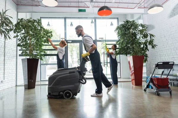 Side View Man Overalls Electrical Floor Scrubber Machine Interracial Colleagues — Stock Photo, Image
