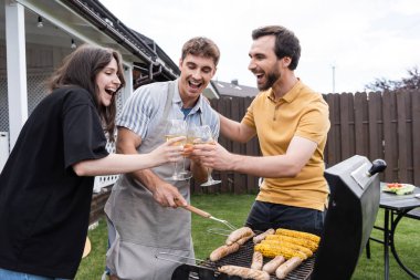 Olumlu arkadaşlar arka bahçede bbq Grill yakınlarında şarapla kadeh kaldırıyorlar. 
