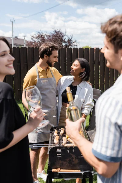 Sonriendo Gente Interracial Hablando Cerca Amigos Borrosos Con Vino Parrilla — Foto de Stock