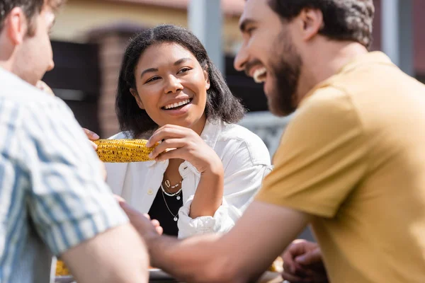 Smiling Racial Woman Holding Corn Picnic Blurred Friends Outdoors — Stock Photo, Image