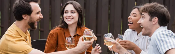 裏庭でパーティー中にワインとグラスを持っている陽気な多民族の友人バナー — ストック写真