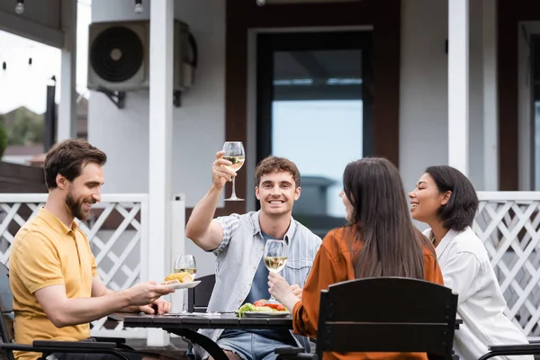 裏庭でのBbqパーティー中に異人種間の友人の近くでワインのグラスを上げる幸せな男 — ストック写真