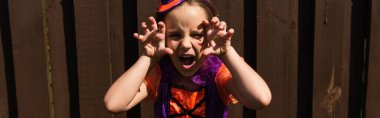 girl in halloween costume growling and showing scary gesture, banner clipart
